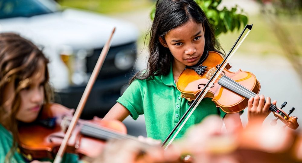 Niñas tocando violín en una clase de música