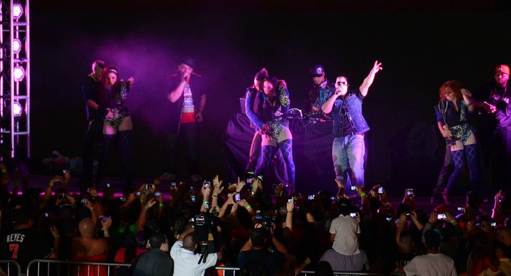 Concierto de reggaetón con luces moradas y público